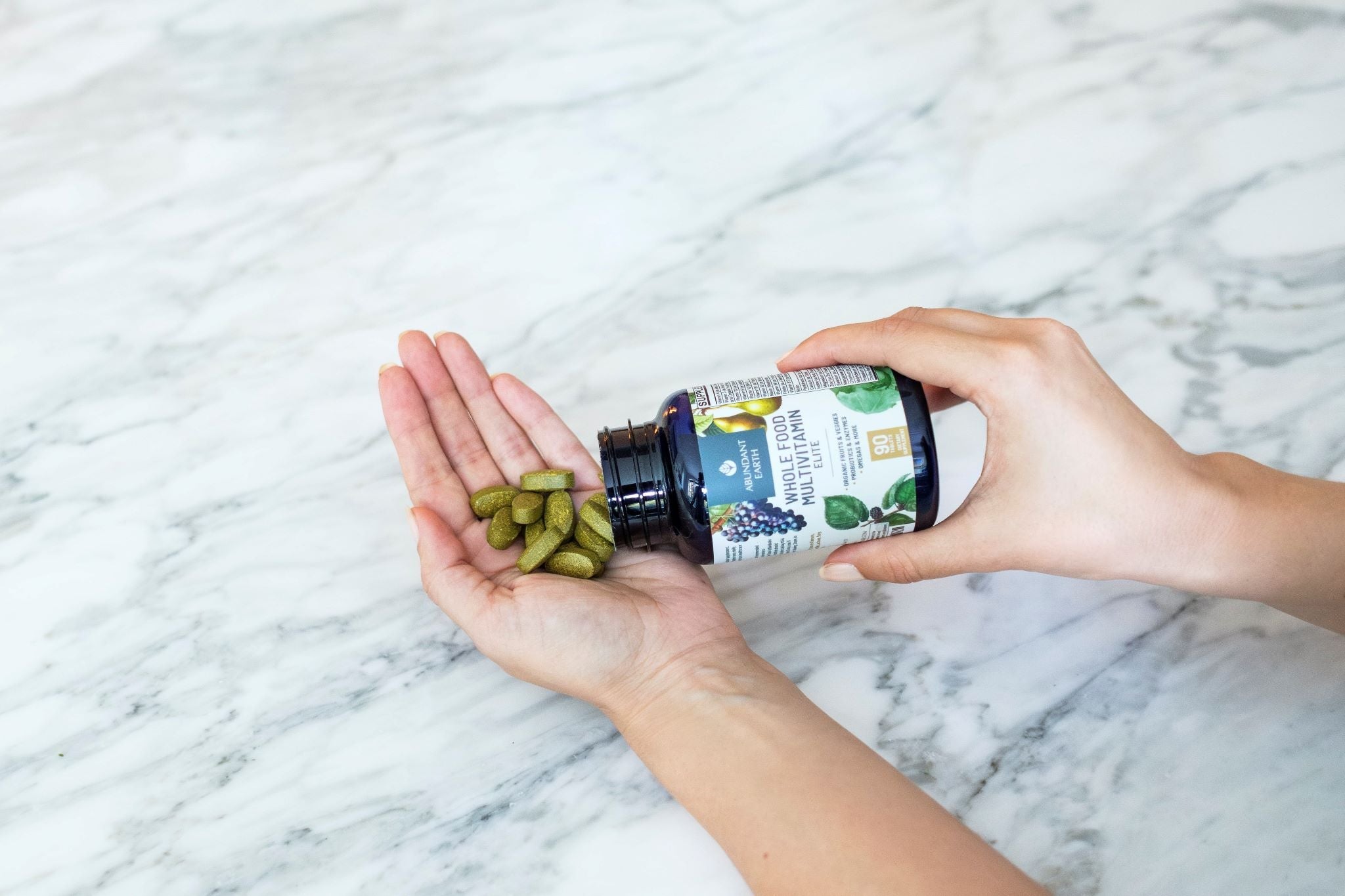Woman's hand holding Abundant Earth Whole Food Multivitamins