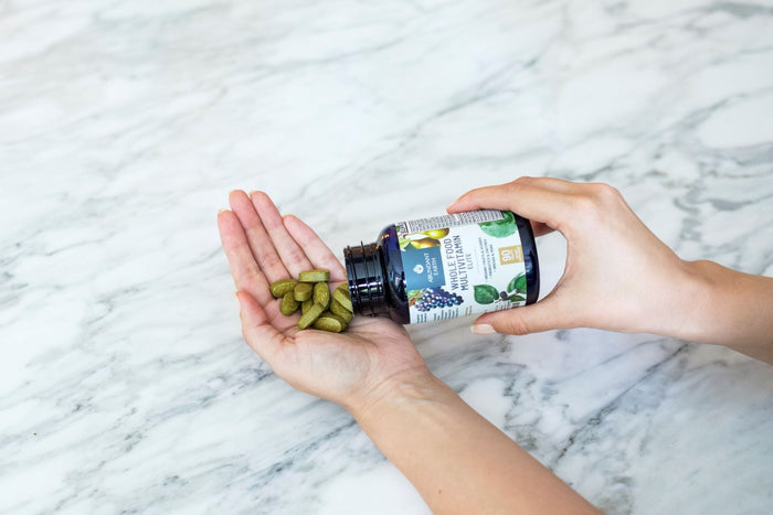 Woman's hand holding Abundant Earth Whole Food Multivitamins